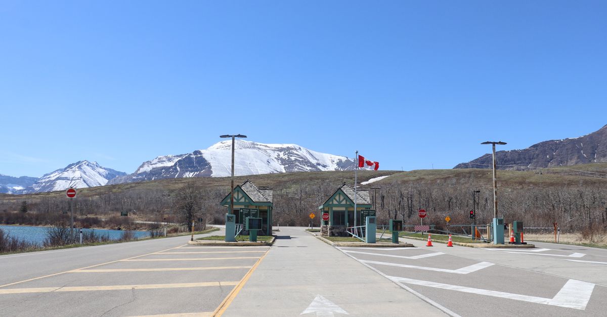 Mountain border crossing road with a small building and vehicles waiting in line
